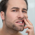 Man checking his teeth and looking disturbed